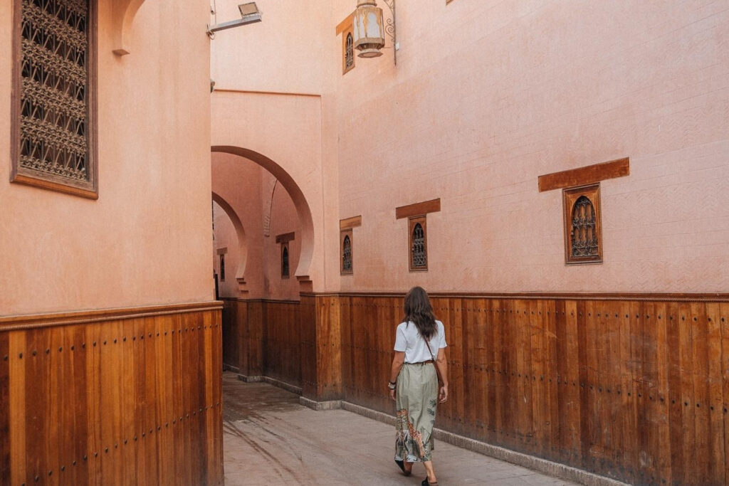 Woman walking through narrow alleyway in the Medina, the best area to stay in Marrakech for cultural immersion